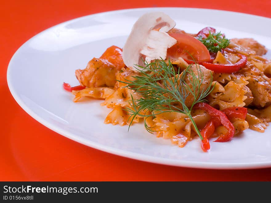 Freshly cooked plate of macaroni with chamignons and tomatoes sprinkled with fresh green herbs.