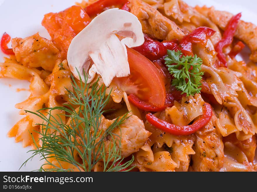 Freshly cooked plate of macaroni with chamignons and tomatoes sprinkled with fresh green herbs.