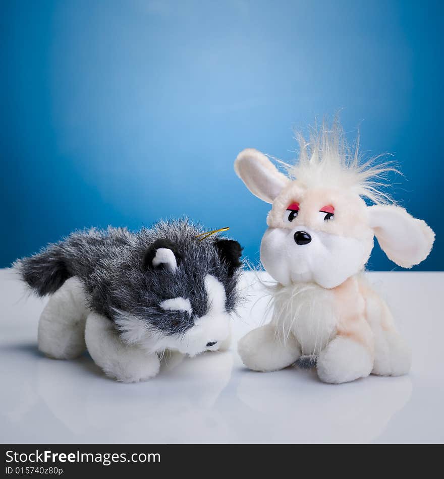 Toy cat and dog on the white reflective table. Toy cat and dog on the white reflective table