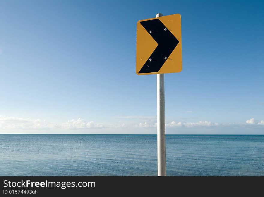 Direction sign in front of calm sea and cloudless sky. Direction sign in front of calm sea and cloudless sky