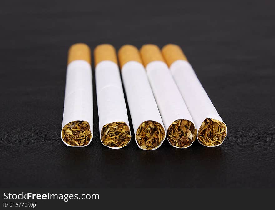 Cigarette tobacco on the black leather background. Cigarette tobacco on the black leather background