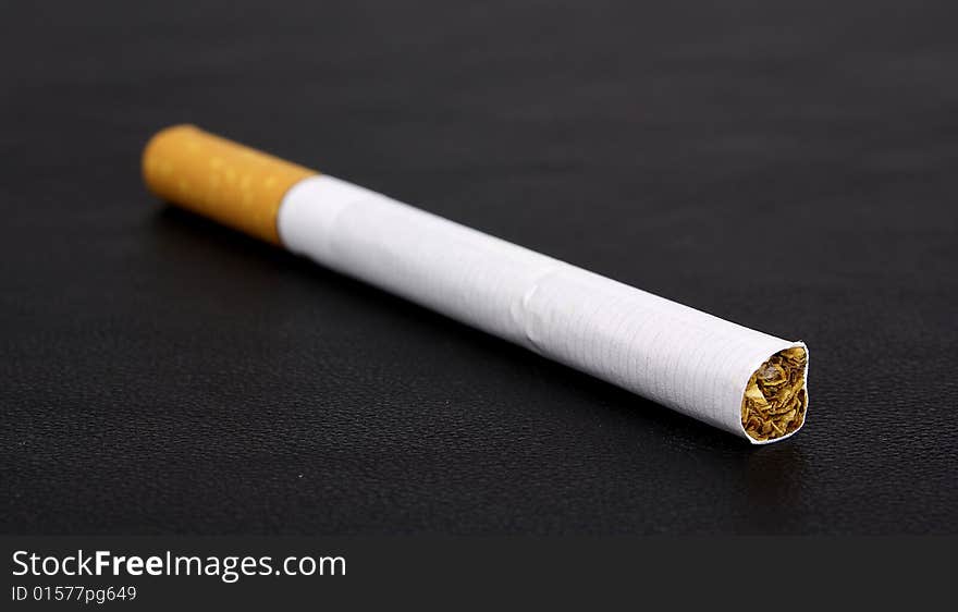 Cigarette tobacco on the black leather background. Cigarette tobacco on the black leather background