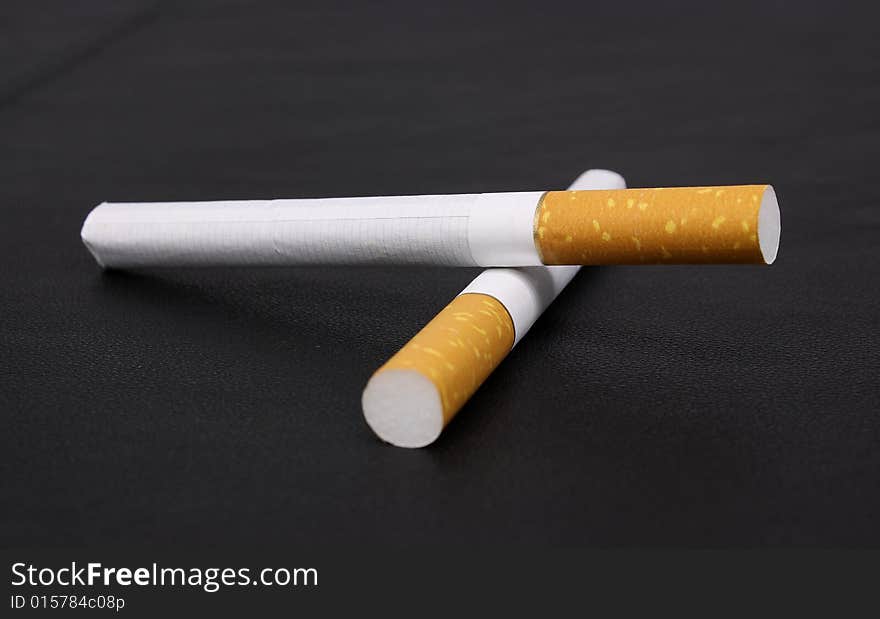 Cigarette tobacco on the black leather background. Cigarette tobacco on the black leather background