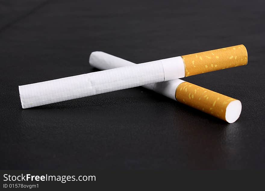 Cigarette tobacco on the black leather background. Cigarette tobacco on the black leather background