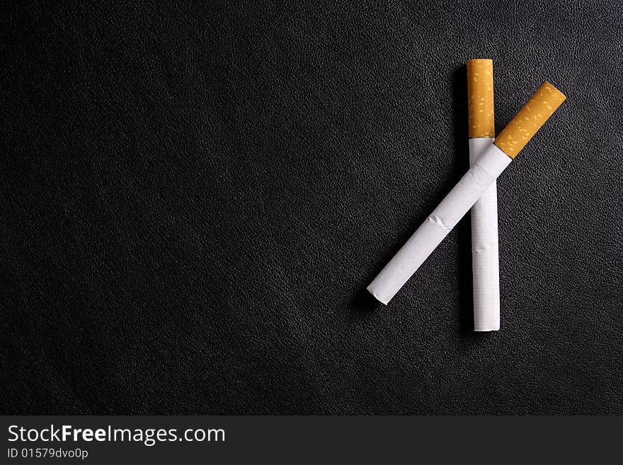 Cigarette tobacco on the black leather background. Cigarette tobacco on the black leather background