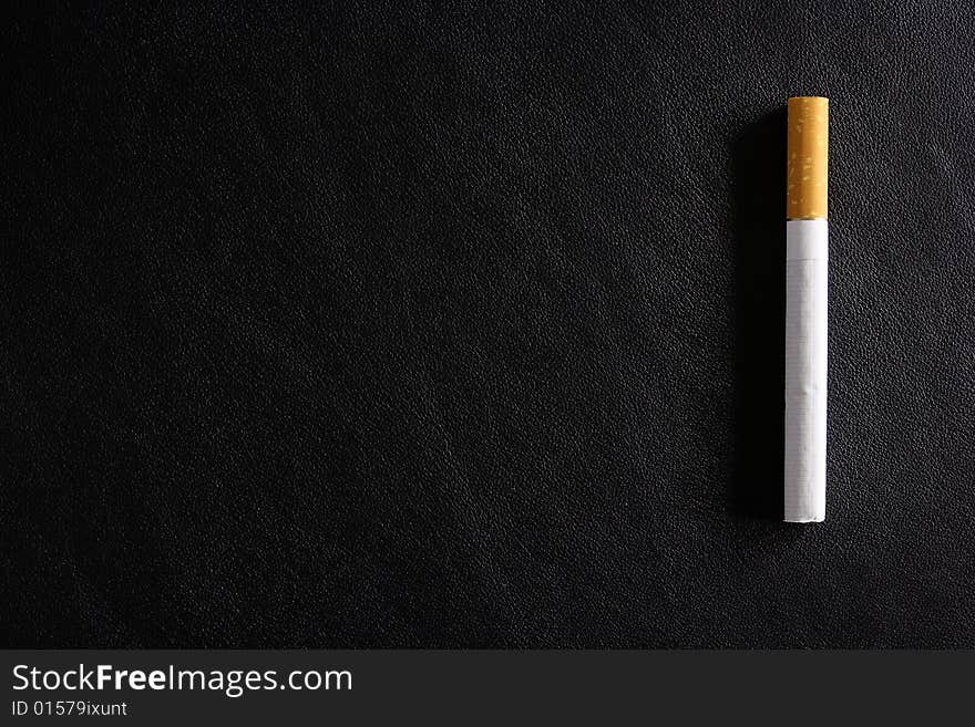 Cigarette tobacco on the black leather background. Cigarette tobacco on the black leather background