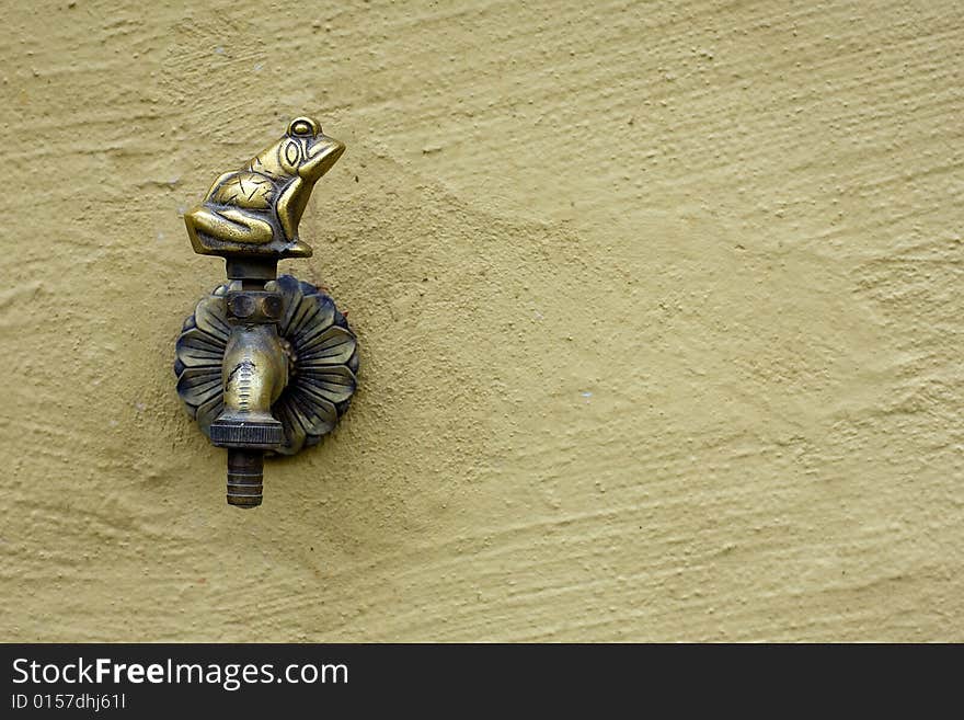 Old bronze faucet with frog form on wall. Old bronze faucet with frog form on wall