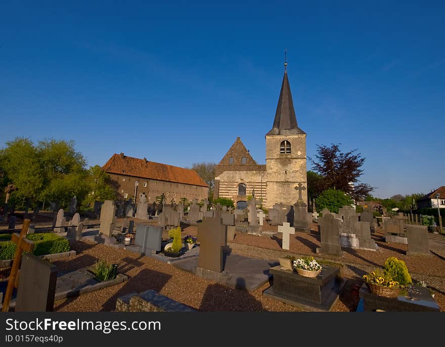 Graveyard on a sunny day and blue sky with a little medieval church in the back