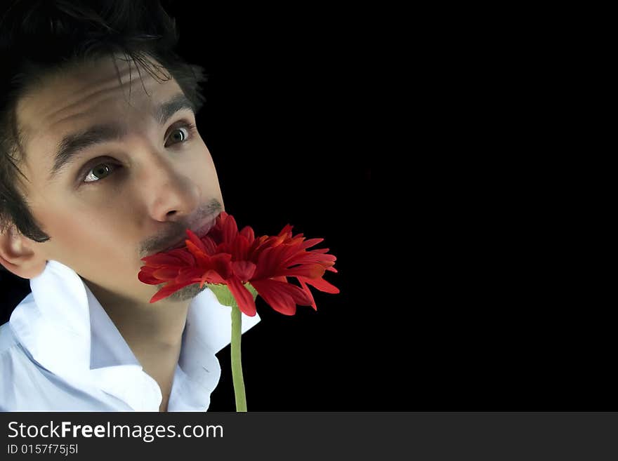 Young man with a red flower isolated on a black background