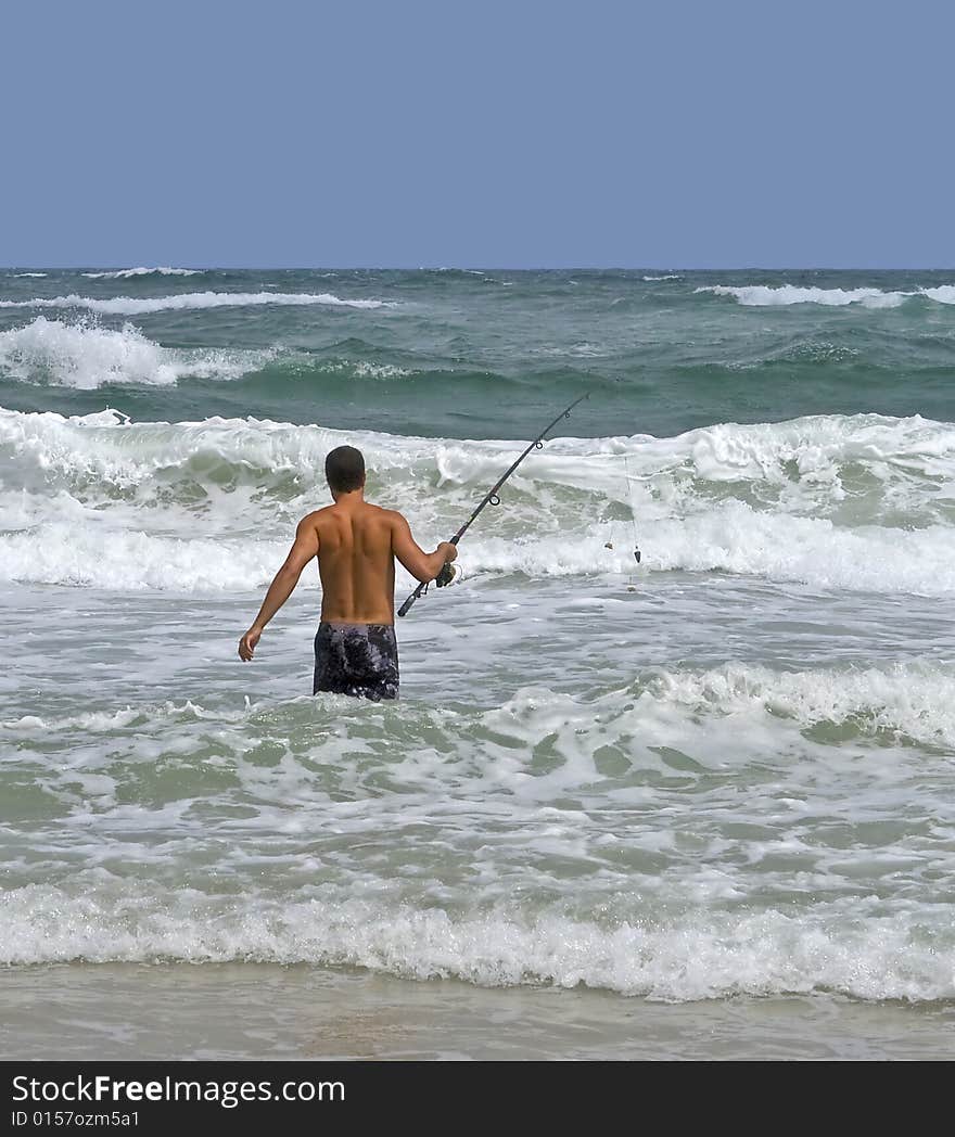 Man surf fishing in the rough surf.