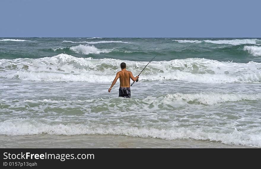 Man surf fishing in the rough surf.