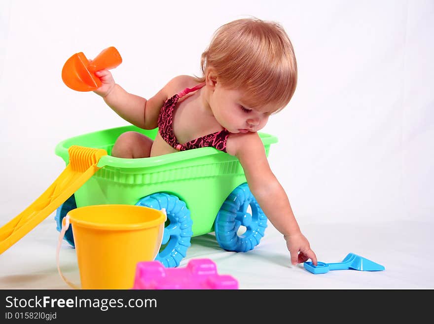 An adorable baby girl sits in a wagon while she plays with her beach toys. An adorable baby girl sits in a wagon while she plays with her beach toys.