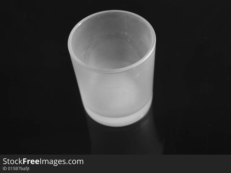 A white glass votive holder on a ultra black background. A white glass votive holder on a ultra black background