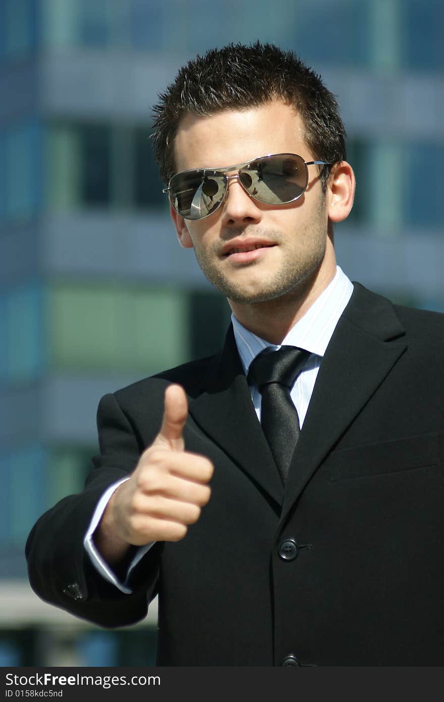 Portrait of a young man with highly successful stretched thumb and sunglasses. Portrait of a young man with highly successful stretched thumb and sunglasses