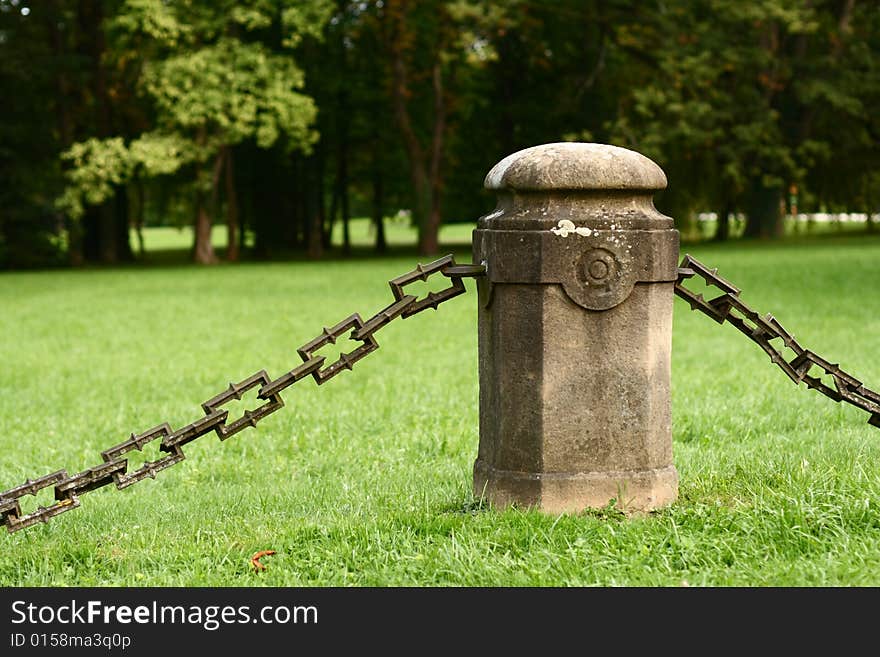 An iron chain hanging from a concrete column.