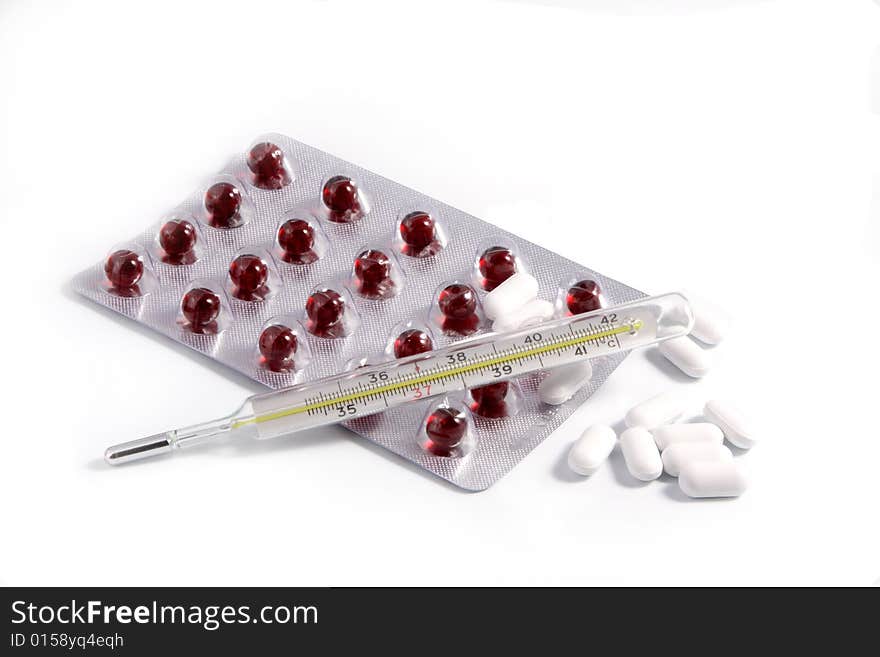 Thermometer, tablets in packing, a syringe on a white background.