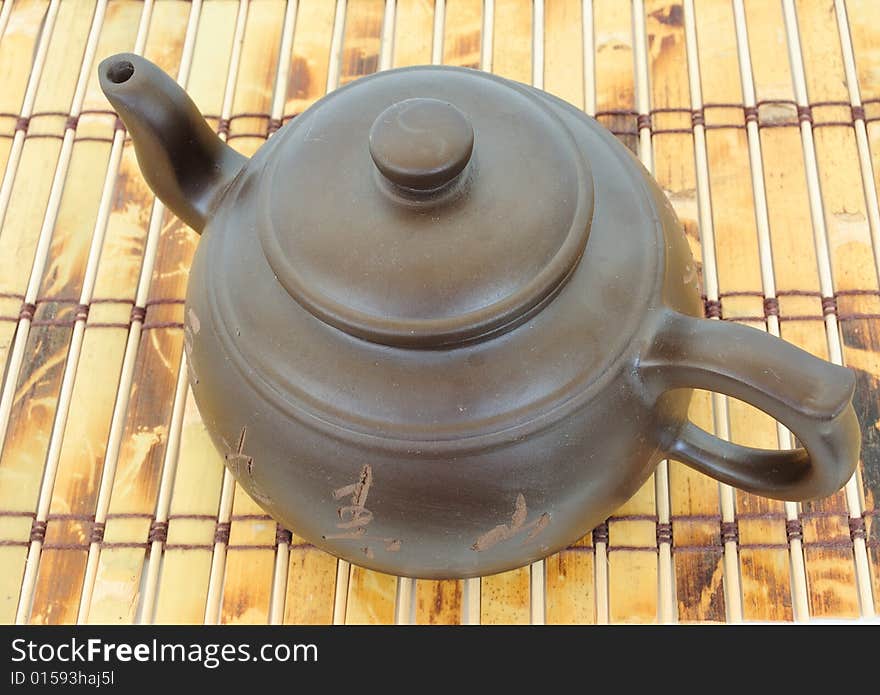 Classic chinese teapot of brown clay over bamboo mat