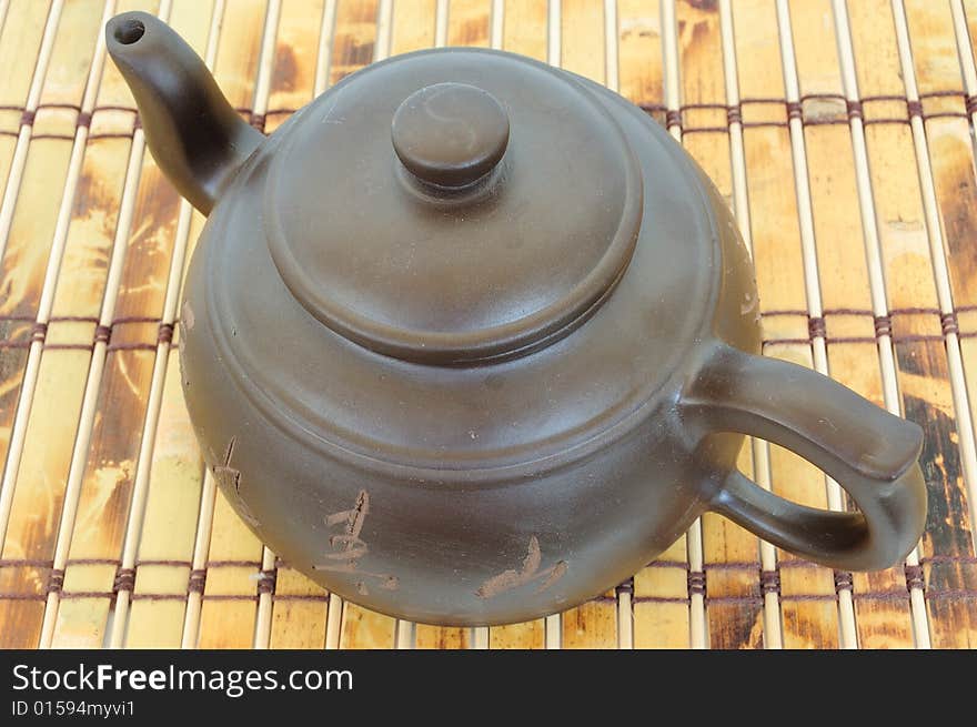 Classic chinese teapot of brown clay over bamboo mat