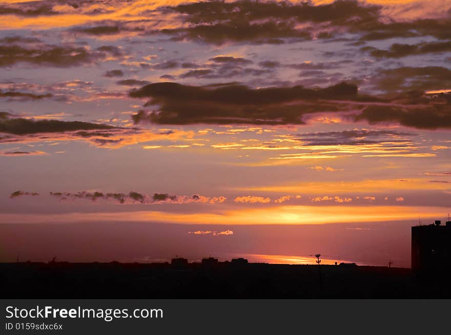 Fleecy clouds of bright city sunset