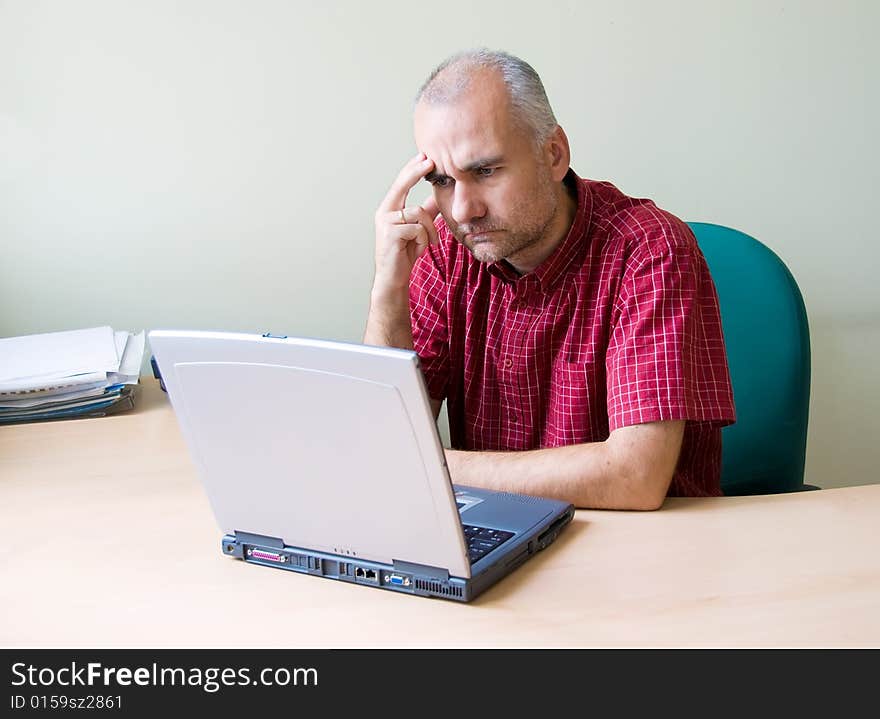 Thoughtful office worker working at the desk with laptop