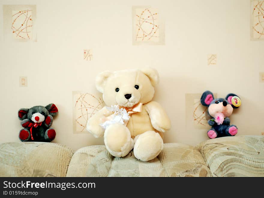 Three toy animals: one white bear and two mice are sitting next to a wall. Three toy animals: one white bear and two mice are sitting next to a wall