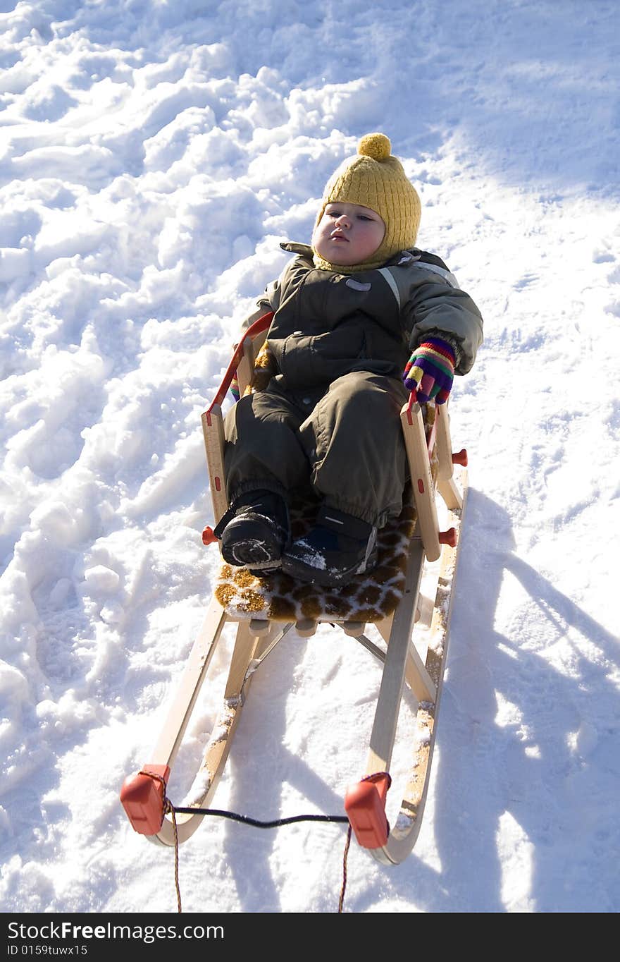 Baby in green coat has rest in sled. Baby in green coat has rest in sled