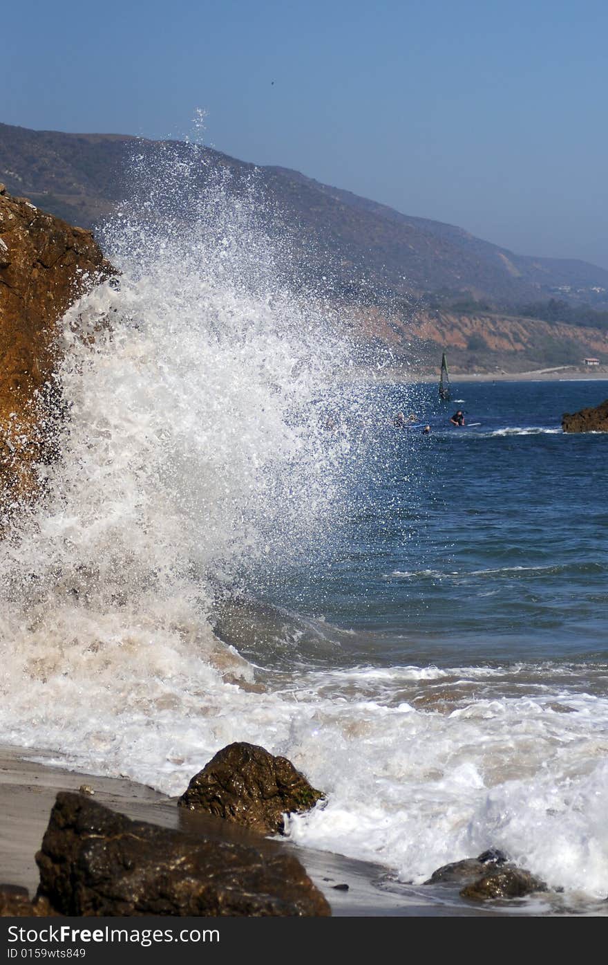 Wave splashing into a rock on malibu beach