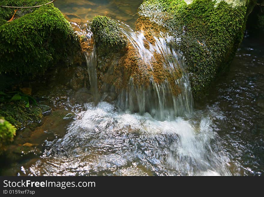 Micro Waterfall in wild forest on sunny day. Micro Waterfall in wild forest on sunny day...