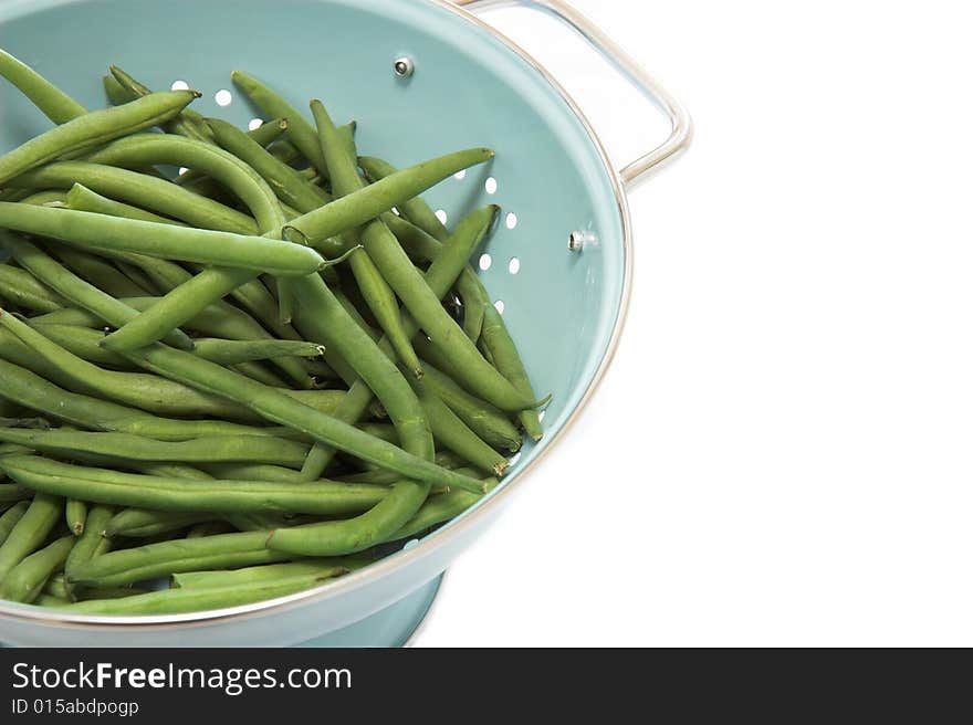 A blue colander full of green beans, isolated on white. A blue colander full of green beans, isolated on white.