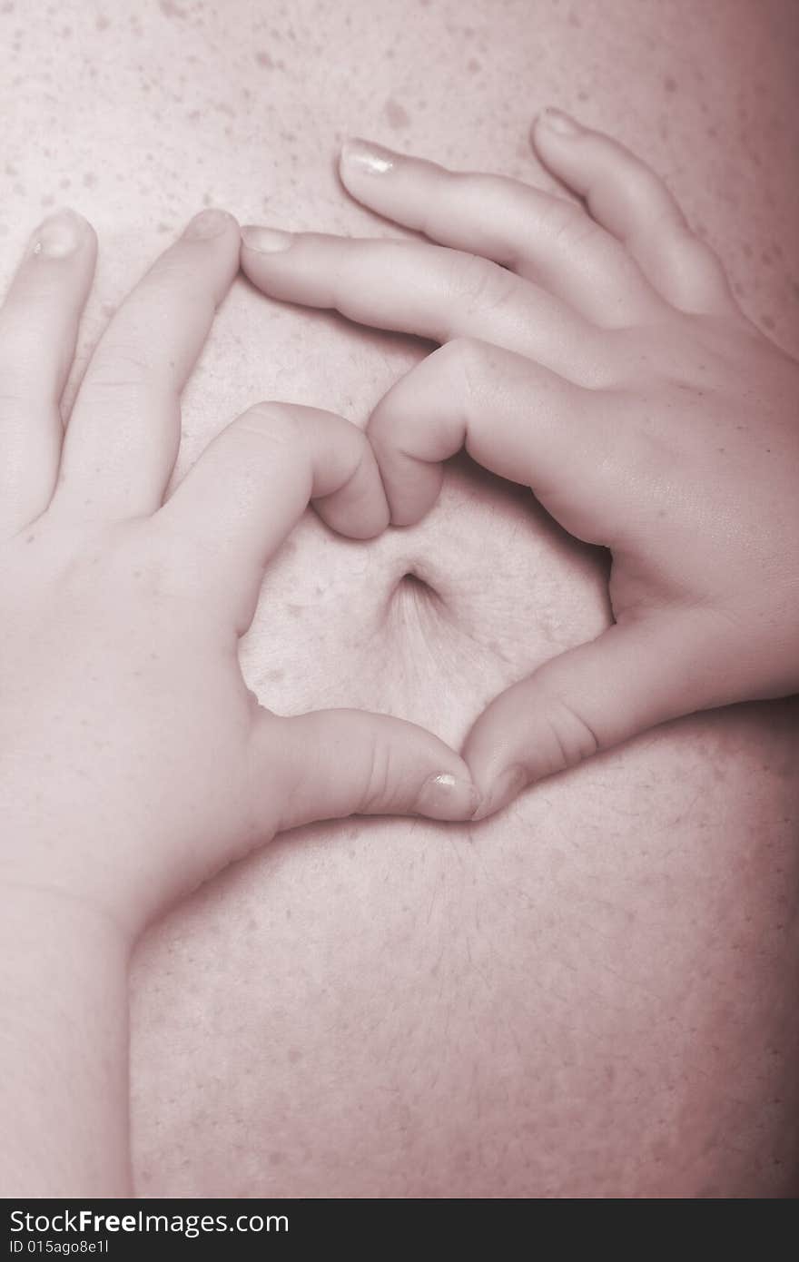 Little girl making a heart out of her fingers on mommy pregnant belly