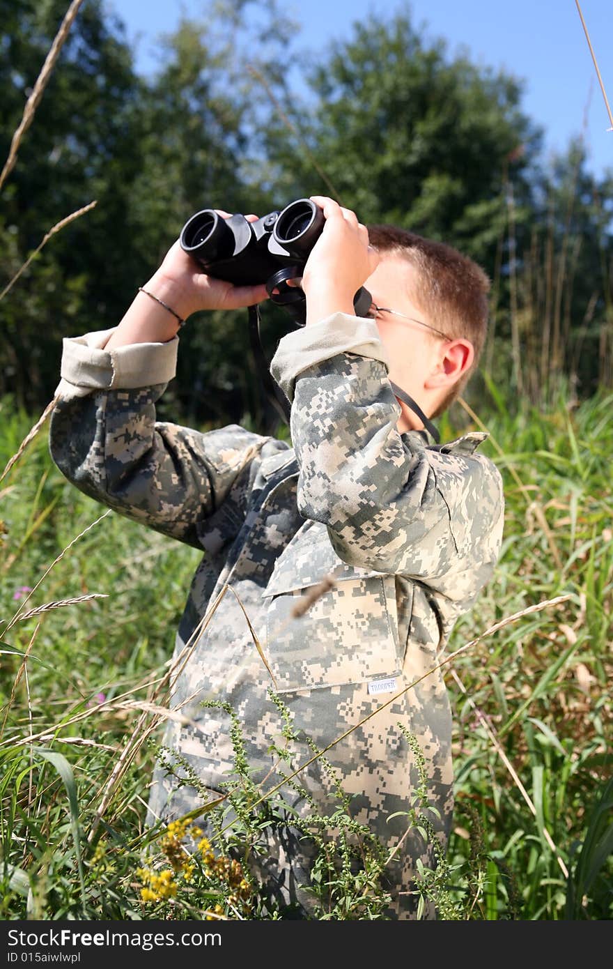 Boy in field looking through binoculars