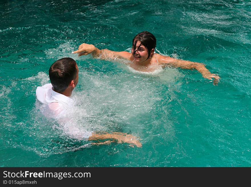 Bride and groom celebrating their wedding day by jumping in a swimming pool. Bride and groom celebrating their wedding day by jumping in a swimming pool.