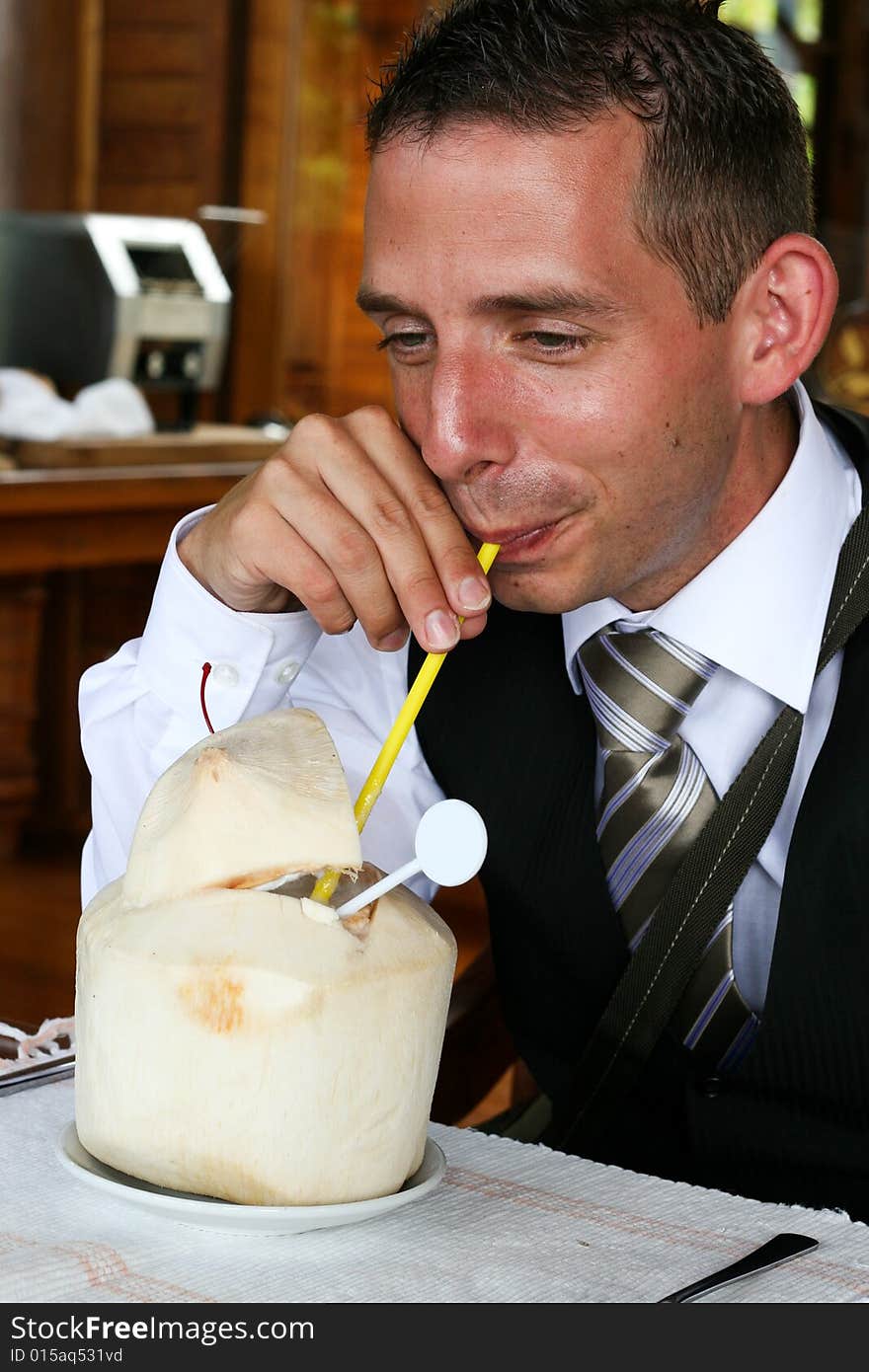 Businessman drinking from a coconut.