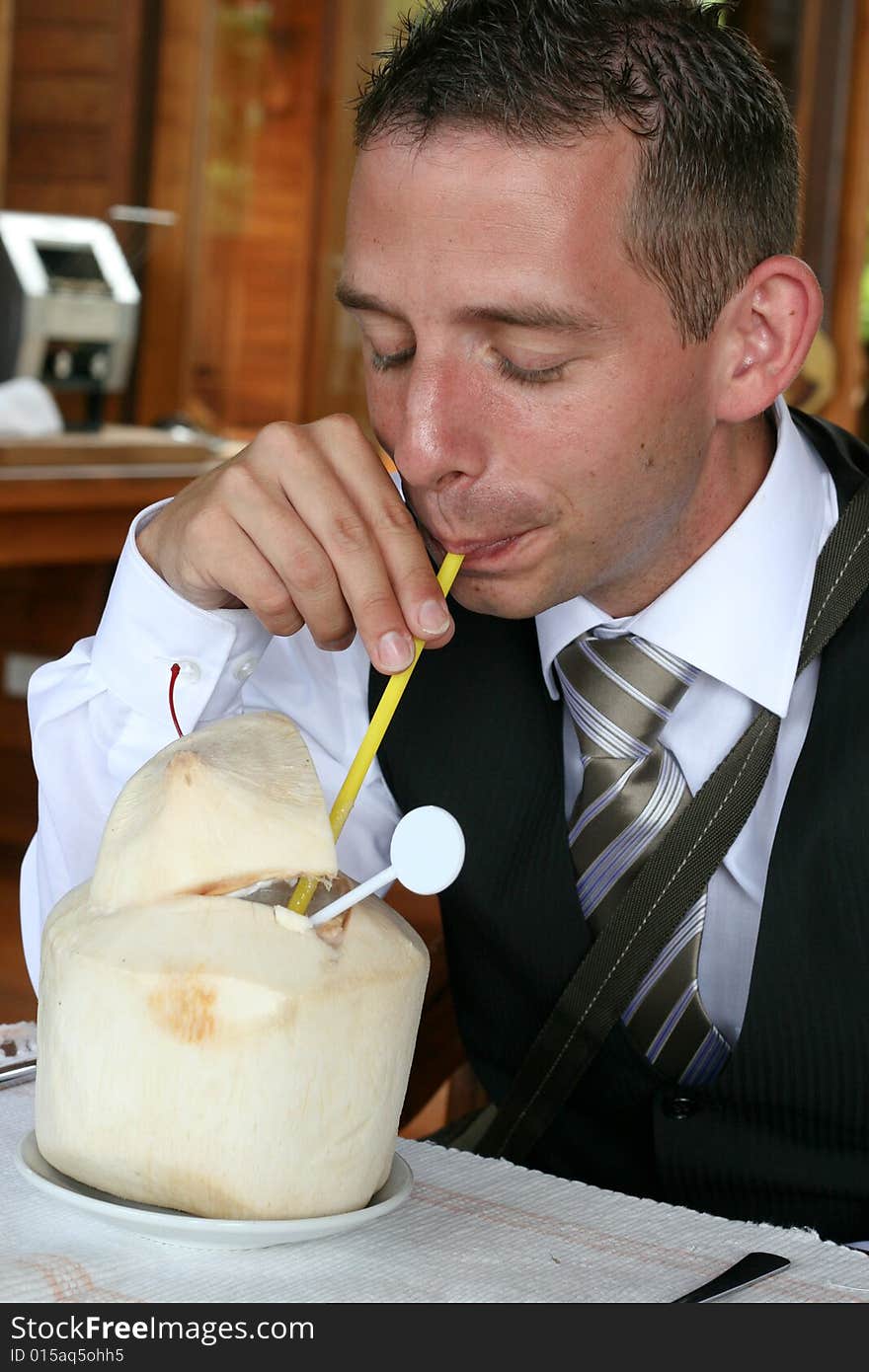 Businessman drinking from a coconut.