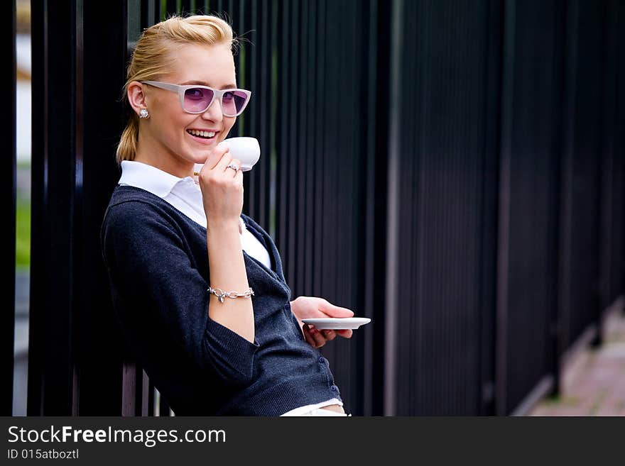 Smiling lovely young woman drinking coffee outside. Smiling lovely young woman drinking coffee outside