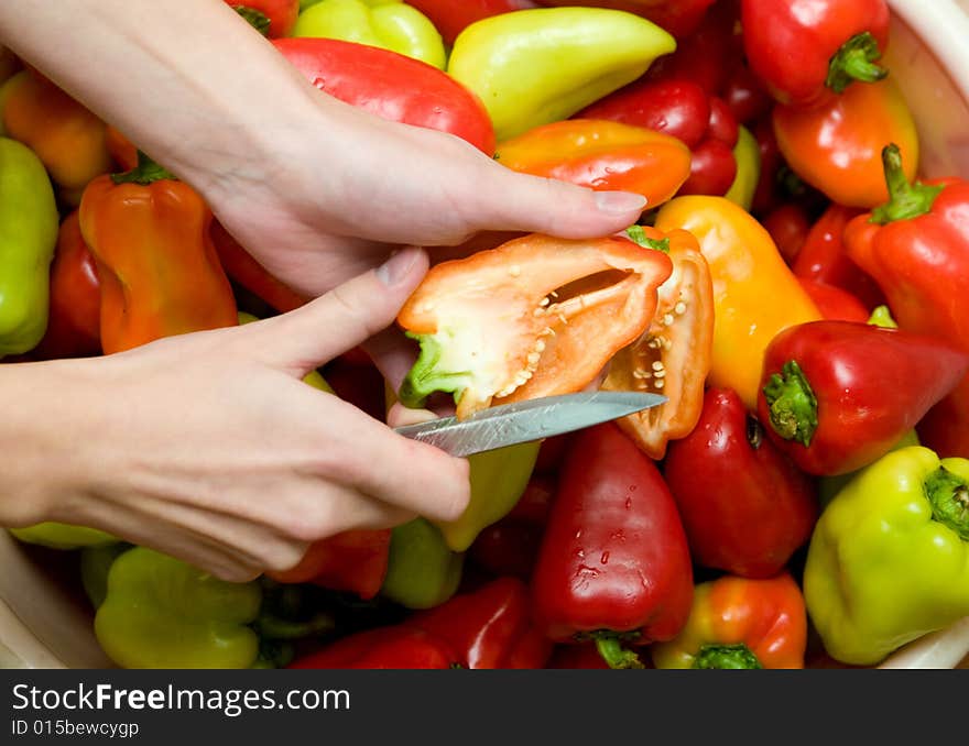 Many colored sweet peppers with hands and knife