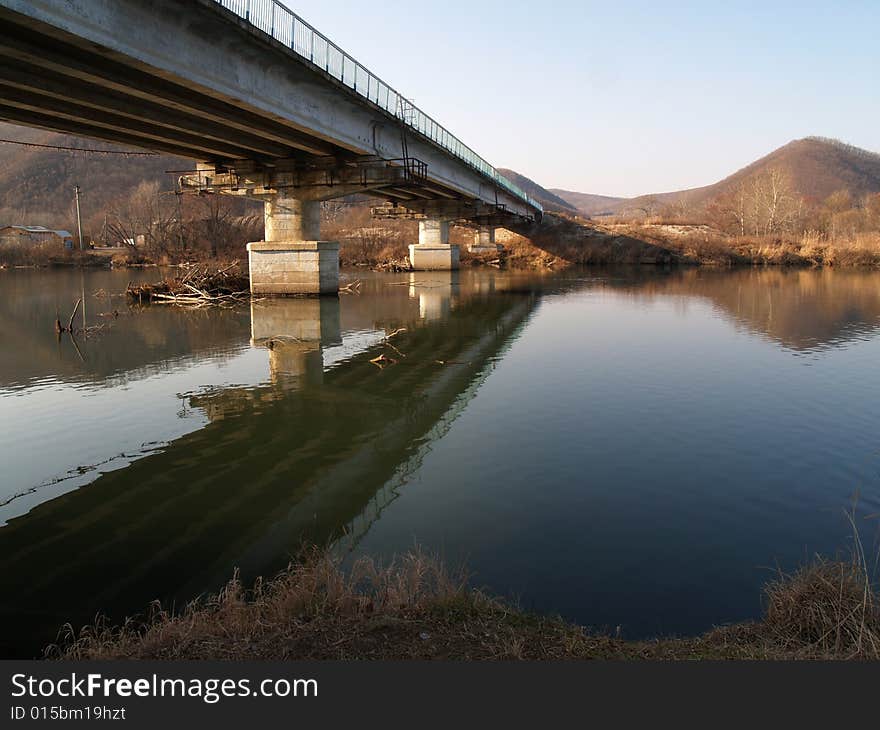 Autumn landscape with the bridge through the river.