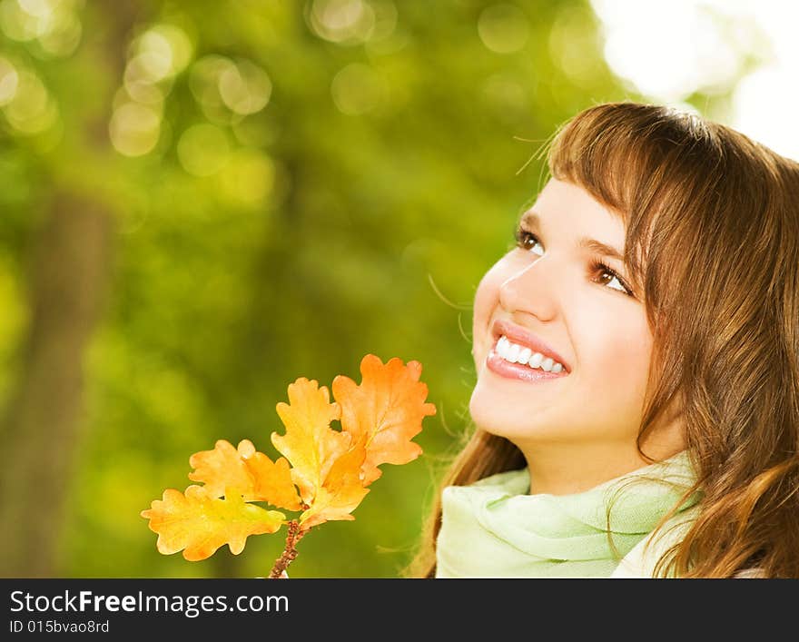 Beautiful romantic brunette with golden autumn leaf close-up portrait