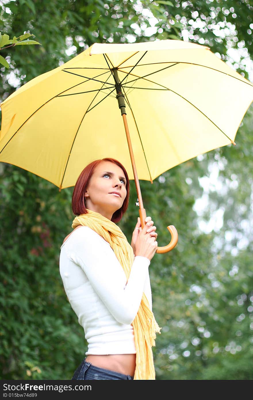 Beautiful young girl under yellow umbrella