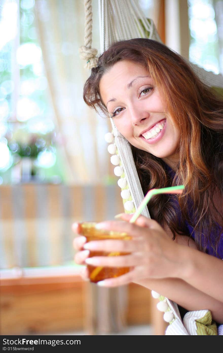 Happy long-haired girl drinking lemonade in comfortable cottage