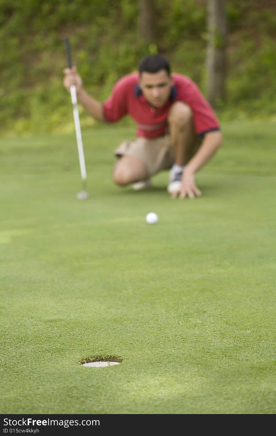 Young man lining up his putt on the green.