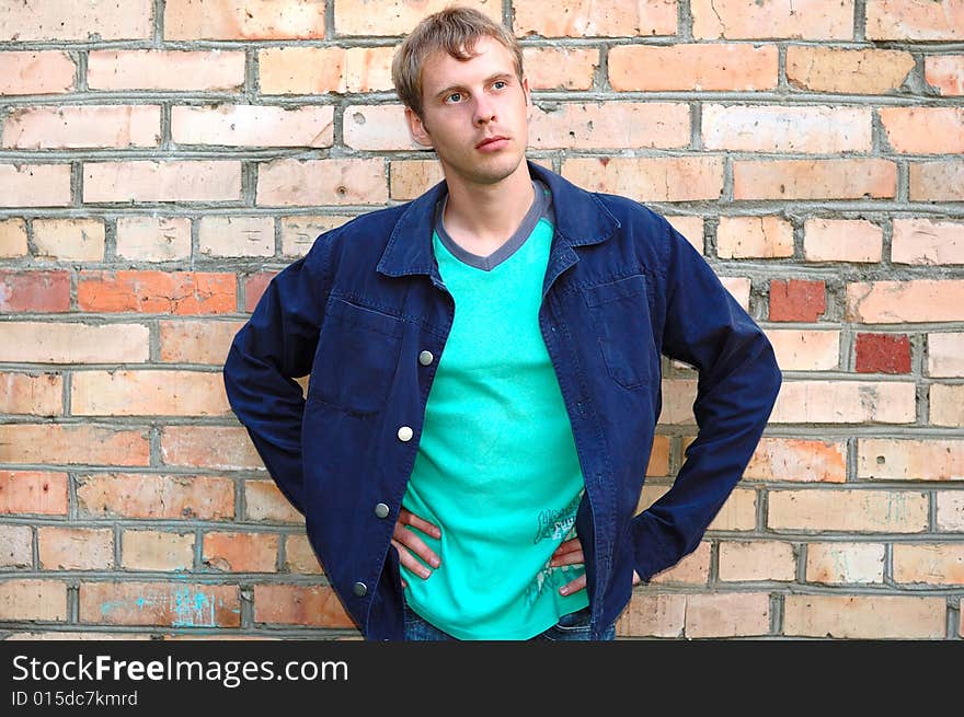 Young stylish man stand near brick wall.