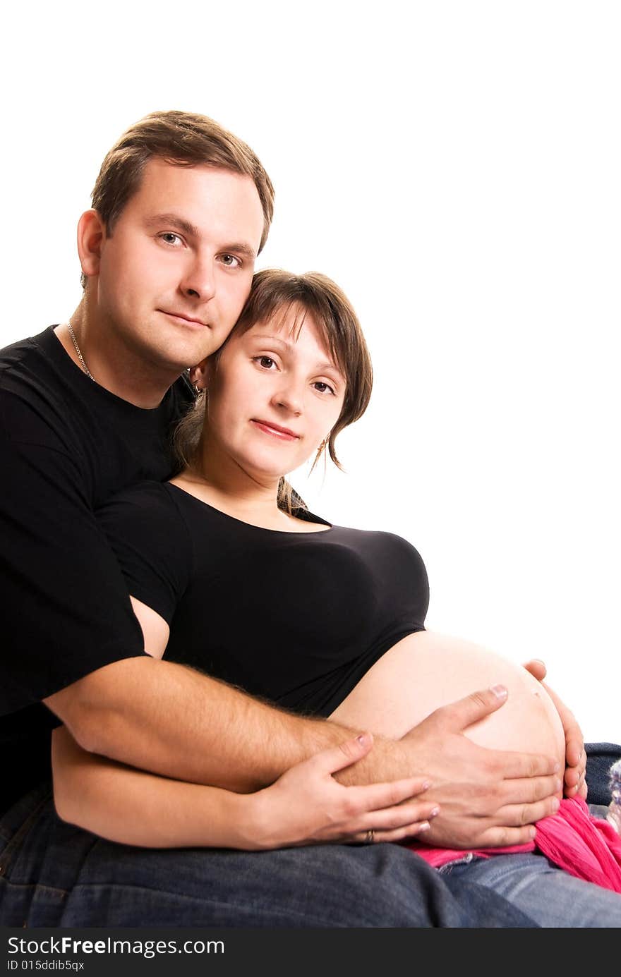 Young man and his pregnant wife embracing isolated against white background