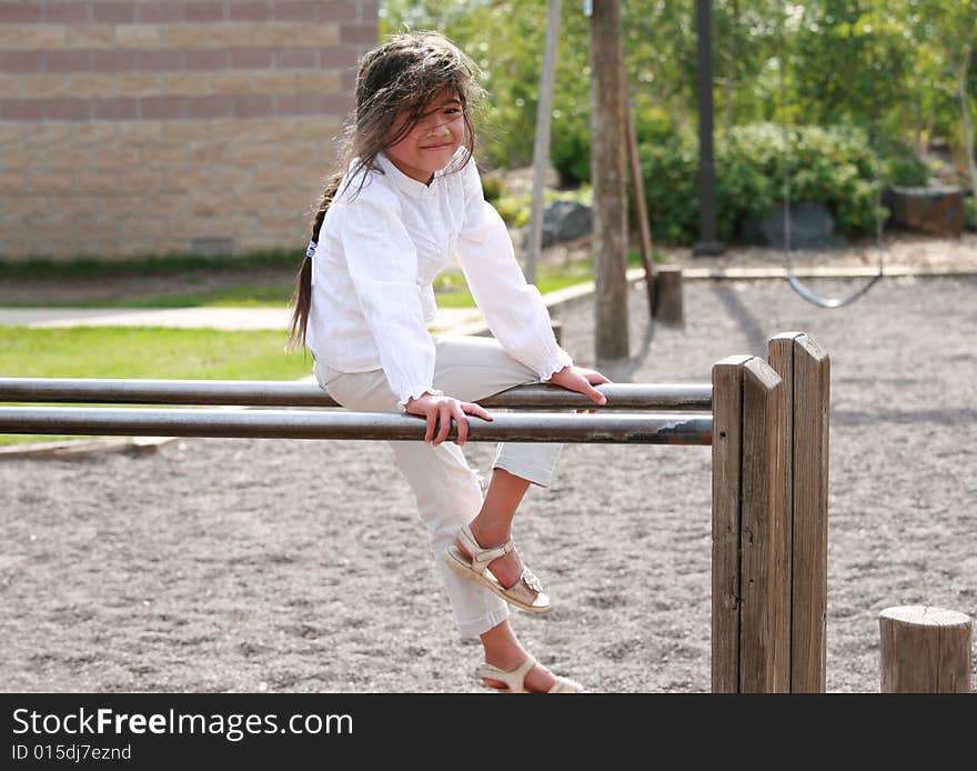 Little girl sitting on top of parallel bars at playground. Little girl sitting on top of parallel bars at playground