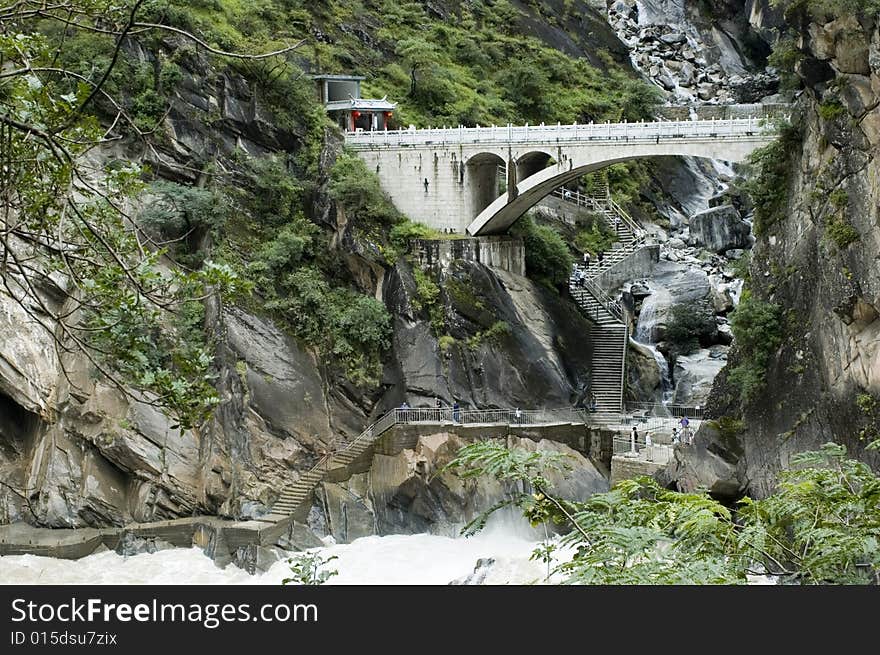 Sino-Tibetan mountains in Yunnan province, near Lijiang city, China. Bridge in ancient Chinese style over river.