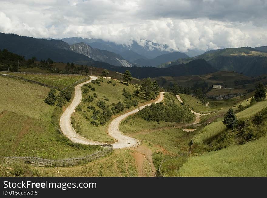 Yunnan province, China - beautiful landscape - roads, trees, meadows and high mountains surrounding village. Yunnan province, China - beautiful landscape - roads, trees, meadows and high mountains surrounding village.