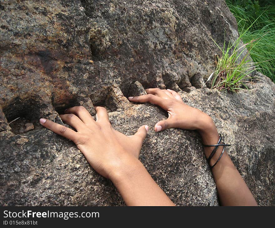 Square pieces have been carved on d rock. The stretched fingers of a teenager just show the youthful exuberance. Square pieces have been carved on d rock. The stretched fingers of a teenager just show the youthful exuberance