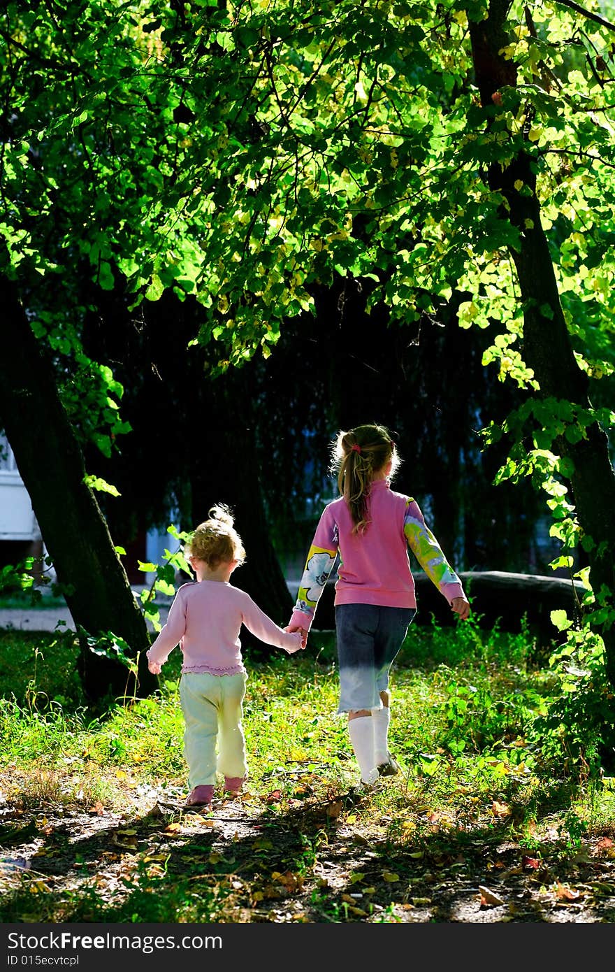 An image of two sisters walking amongst trees