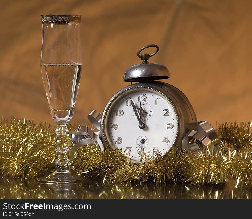 Old Alarm Clock showing few minutes to twelve with glass of champagne