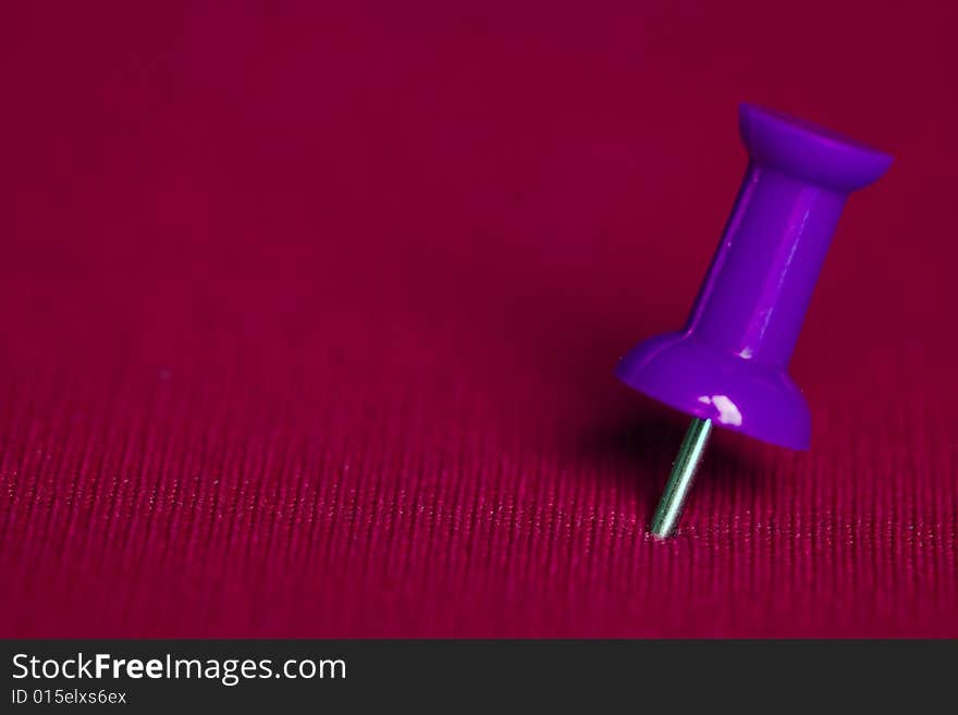 Close up of purple push pin on pink background. Close up of purple push pin on pink background